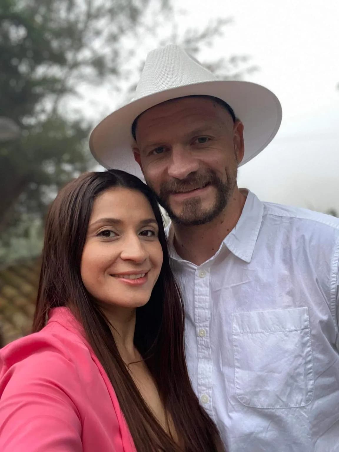 Florencia and Sean close together for a selfie outdoors, he in a wide white hat